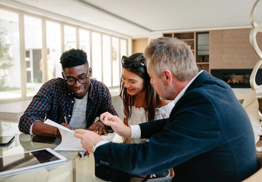 Parent and college student review insurance cards and health plan documents at a kitchen table.