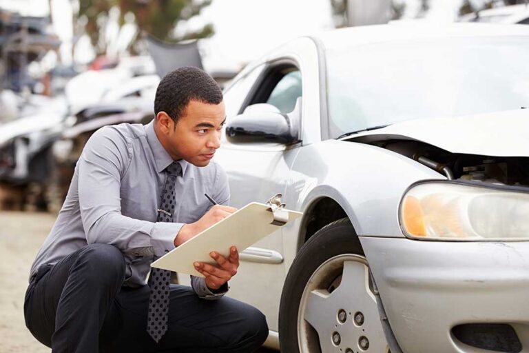 A person holding car keys with a clipboard and insurance paperwork on a table.